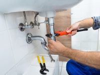 Male Plumber Fixing Sink In Bathroom